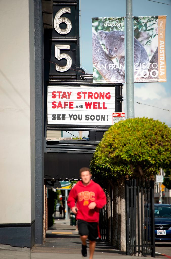 A man jogs by a theatre posting sign of support on it's marquis in a mostly empty San Francisco, California on March 17, 2020. - Millions of San Francisco area residents last Monday were ordered to stay home to slow the spread of the deadly coronavirus as part of a lockdown effort covering a section of California including Silicon Valley. (Photo by Josh Edelson / AFP) (Photo by JOSH EDELSON/AFP via Getty Images)