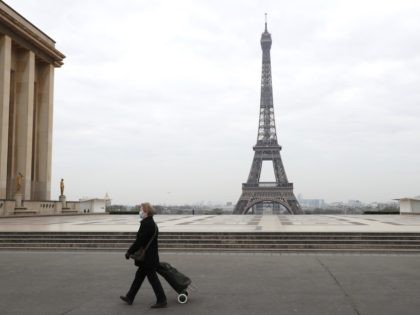 A woman with protective mask walks by the Esplanade du Trocadero square near the Eiffel Tower in Paris, on March 18, 2020 in Paris as a strict lockdown comes into in effect in France to stop the spread of COVID-19, caused by the novel coronavirus. - A strict lockdown requiring …