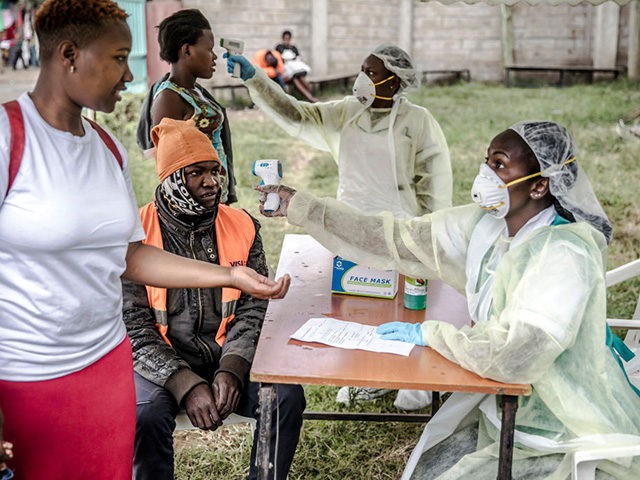 Health personnel measure the temperature of a visitor at the entrance of the Mbagathi Hospital in Nairobi, Kenya on March 18, 2020. - The Government of Kenya confirmed new positive cases of COVID-19 coronavirus on March 18, 2020, bringing the total official number of cases in the East African country …