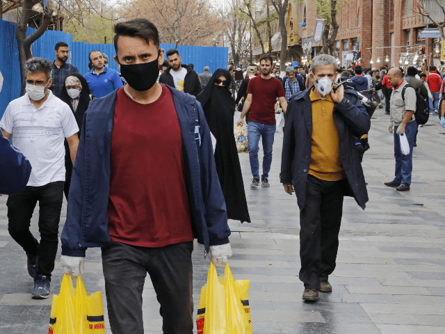 Iranians, some wearing protective masks,walk outside the capital Tehran's grand bazaar, during the Covid-19 coronavirus pandemic crises, on March 18, 2020. - Iran said its novel coronavirus death toll surpassed 1,000 today as President Hassan Rouhani defended the response of his administration, which has yet to impose a lockdown. The …