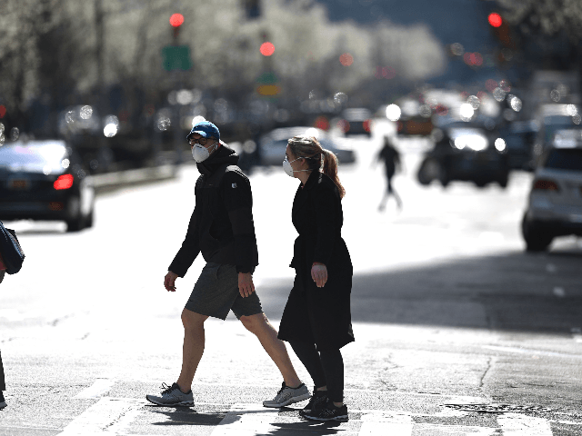 A couple wearing masks cross a street in manhattan on March 18, 2020 in New York City. - T