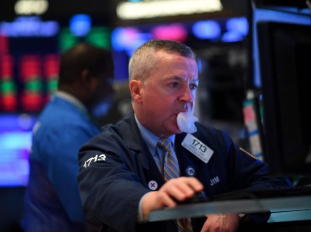 A traders chews gum as he works during the opening bell at the New York Stock Exchange (NYSE) on March 19, 2020 at Wall Street in New York City. - Wall Street stocks fell again early Thursday as central banks unveiled new stimulus measures and US jobless claims showed an …