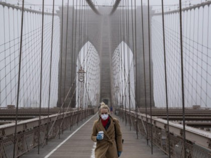 NEW YORK, NY - MARCH 20: A woman wearing a mask walks the Brooklyn Bridge in the midst of