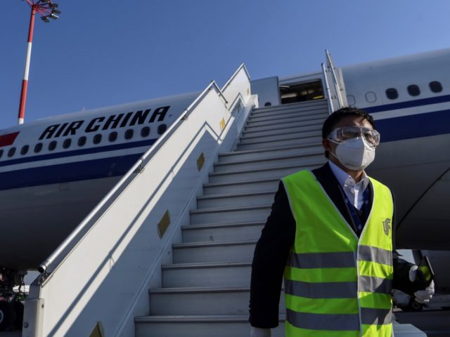 A member of staff, wearing a facemask for protective measures, disembarks from an Air China airbus carrying 500.000 protective masks at the Athens international airport, on March 21, 2020, as part of aid measures from China, to help the country and Europe to fight against the spread of the Covid-19, …