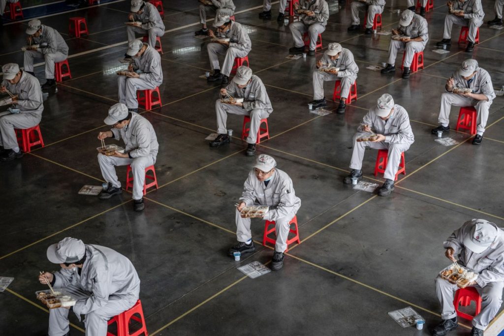 TOPSHOT - This photo taken on March 23, 2020 shows employees eating during lunch break at an auto plant of Dongfeng Honda in Wuhan in China's central Hubei province. - People in central China, where the COVID-19 coronavirus was first detected, are now allowed to go back to work and public transport has restarted, as some normality slowly returns after a two-month lockdown. (Photo by STR / AFP) / China OUT (Photo by STR/AFP via Getty Images)