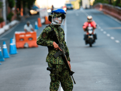 A policeman wearing a facemask stands guard at a checkpoint after the government imposed an enhanced quarantine as a preventive measure against the COVID-19 novel coronavirus in Manila on March 25, 2020. (Photo by Ted ALJIBE / AFP) (Photo by TED ALJIBE/AFP via Getty Images)