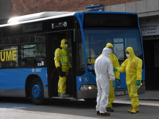 Members of Spanish Military Emergencies Unit (UME) wearing protective suits stand outside a bus used to transport patients from the San Carlos Clinic Hospital to a temporary hospital set-up for coronavirus patients at the Ifema convention and exhibition center in Madrid, on March 29, 2020. - Spain confirmed another 838 …