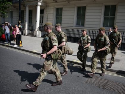 TOPSHOT - British Army soldiers are led by a police officer into Buckingham Palace in central London on May 24, 2017. - Britain deployed soldiers to key sites Wednesday and raised its terror alert to the maximum after the Manchester suicide bombing by Salman Abedi, reportedly a Briton of Libyan …