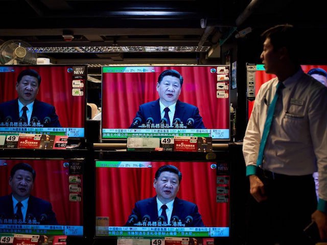 An electronics shop employee in Hong Kong on October 18, 2017 looks at television sets showing a news report on China's President Xi Jinping's speech at the opening session of the Chinese Communist Party's five-yearly Congress at the Great Hall of the People in Beijing. President Xi Jinping declared China …