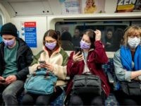 Commuters wear masks as a precaution whilst travelling on a London Underground metro train in the morning in central London on March 18, 2020 as people take precautions amid the coronavirus outbreak. - The British government will on Wednesday unveil a raft of emergency powers to deal with the coronavirus …