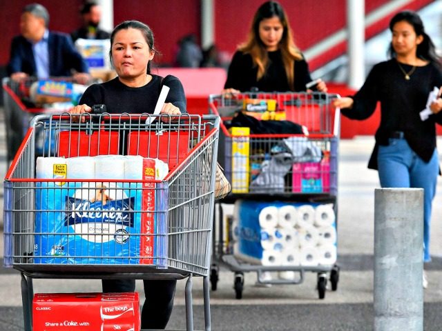 People leave a Costco warehouse with rolls of toilet paper amongst their groceries in Melbourne on March 5, 2020. – COVID-19 coronavirus fears have triggered runs on several products, including hand sanitisers and face masks, with images of shoppers stacking trolleys with toilet rolls spreading on social media. (Photo by …