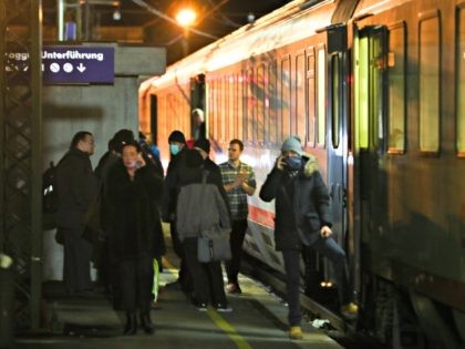 A people stand on the platform near a train stoped by authorities at the train station on