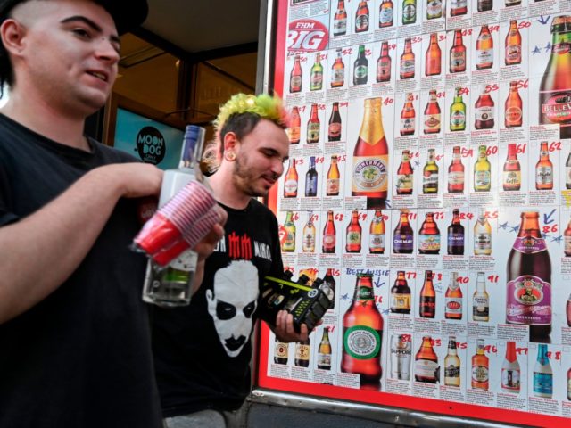 Two men leave a "bottle shop" displaying a sign showing dozens of beers for sale, in Melbo