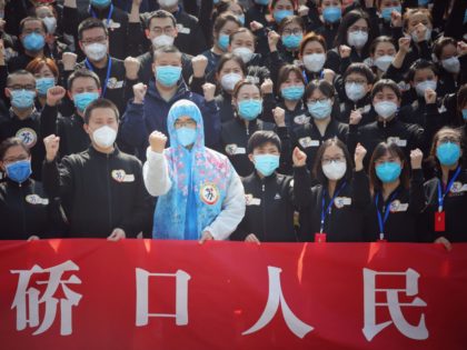 TOPSHOT - Members of a medical assistance team from Jiangsu province chant slogans at a ceremony marking their departure after helping with the COVID-19 coronavirus recovery effort, in Wuhan, in China's central Hubei province on March 19, 2020. - Medical teams from across China began leaving Wuhan this week after …