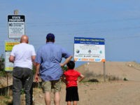 People read signs near a constuction site off Avenue 12 in Madera, California just north of Fresno on the California High Speed-Railway on May 5, 2019. - For more than five years residents and businesses have been disrupted and relocated up and down California's central San Joaquin Valley from the …