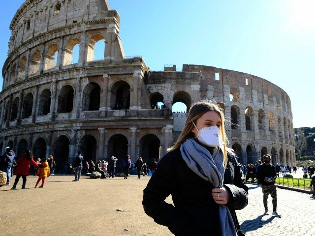 Tourist wearing a protective respiratory mask tours outside the Colosseo monument (Colisee, Coliseum) in downtown Rome on February 28, 2020 amid fear of Covid-19 epidemic. - Since February 23, more than 50,000 people have been confined to 10 towns in Lombardy and one in Veneto -- a drastic measure taken …