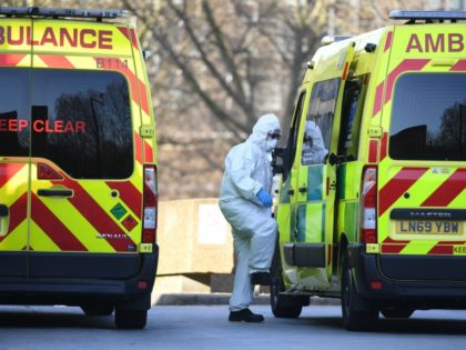 A member of the ambulance service wearing personal protective equipment is seen leading a