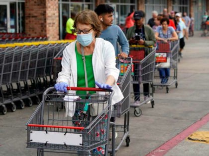 Ruth Flavelle wears a mask and gloves as she enters an H-E-B grocery after waiting in line with more than 150 people Tuesday, March 17, 2020, in Spring, Texas. Grocery store executives and city officials reassured the community, on Monday, that plenty of food will be available in their stores …