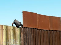 TOPSHOT - A man crosses over the US/Mexico border fence from Mexicali to Calexico, at Mexicali, Baja California state, Mexico, on February 11, 2020. (Photo by Guillermo Arias / AFP) (Photo by GUILLERMO ARIAS/AFP via Getty Images) coronavirus