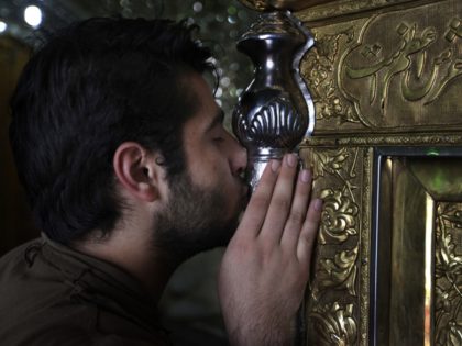 A Shiite Iranian man kisses the grave of Saint Ali Akbar shrine, in northern Tehran, Iran,