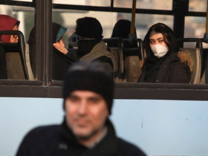 Wearing a face mask, a woman travels on a public bus at a square in western Tehran, Iran,