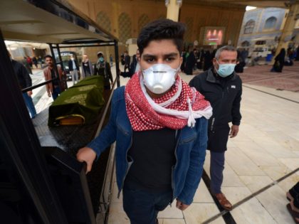 Iraqi mourners, wearing masks, walk on February 25, 2020 with the coffin of a deceased rel