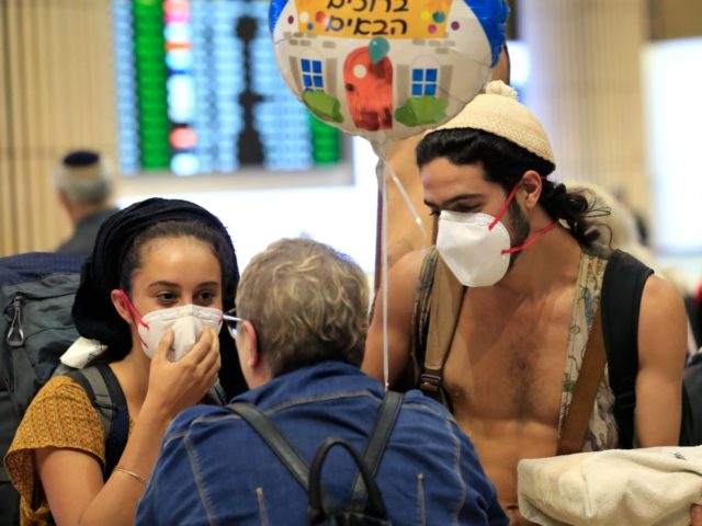 A young couple wearing protective masks are greeted upon arrival at Ben Gurion airport in