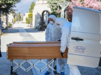 Undertakers wearing a face mask and overalls unload a coffin out of a hearse on March 16, 2020 at the Monumental cemetery of Bergamo, Lombardy, as burials of people who died of the new coronavirus are being conducted at the rythm of one every half hour. (Photo by Piero Cruciatti …