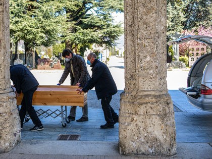 Undertakers wearing a face mask move a coffin out of a hearse on March 16, 2020 at the Monumental cemetery of Bergamo, Lombardy, as burials of people who died of the new coronavirus are being conducted at the rythm of one every half hour. (Photo by Piero Cruciatti / AFP) …