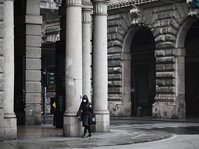 A woman wearing a protection mask walks near Piazza de Ferrari in Genoa, Liguria, on March 13, 2020 as Italy shut all stores except for pharmacies and food shops in a desperate bid to halt the spread of a coronavirus. (Photo by Marco BERTORELLO / AFP) (Photo by MARCO BERTORELLO/AFP …