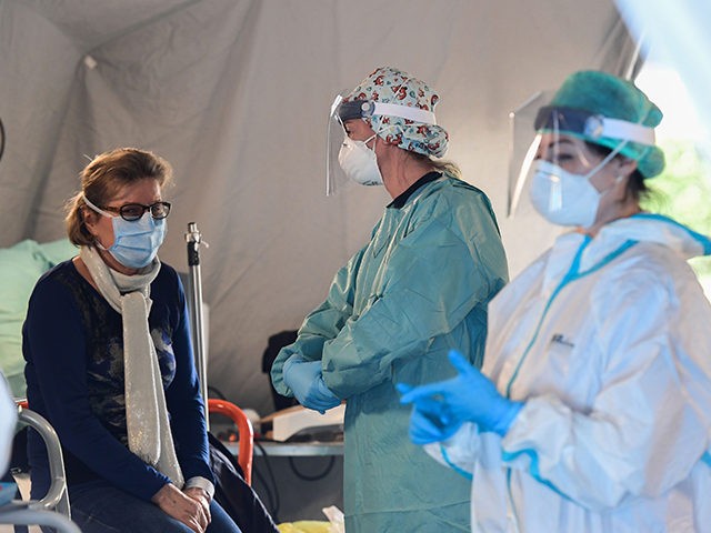 A patient sits in a tent to be tested for new coronavirus, at a temporary emergency structure set up outside the accident and emergency department, where any new arrivals presenting suspect symptoms are being tested, at the Brescia hospital, Lombardy, on March 13, 2020. (Photo by Miguel MEDINA / AFP) …