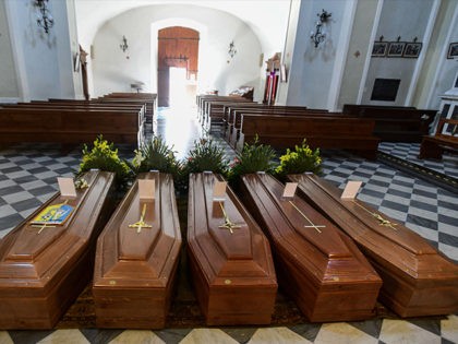 This picture taken on March 21, 2020 shows coffins on the ground of the church in Serina,