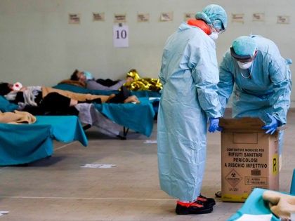 Paramedics carry an hazardous medical waste box as patients lie on camping beds, in one of