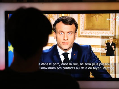 French President Emmanuel Macron is seen on a television screen as he speaks during a tele