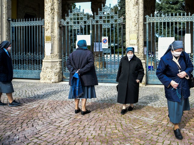 Nuns wearing a face mask wait outside the closed Monumental Cemetery of Bergamo, Lombardy,