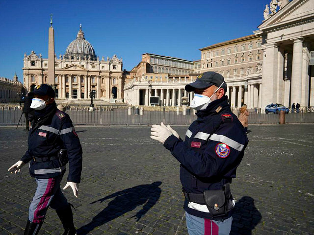 Police officers wearing masks patrol an empty St. Peter's Square at the Vatican, Wednesday