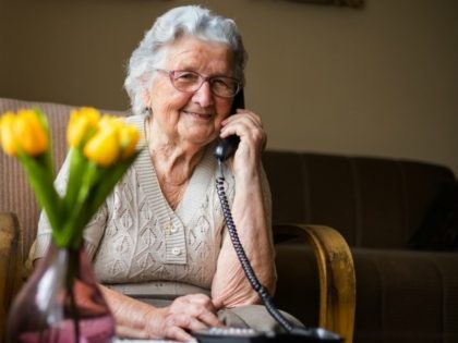 Happy senior woman talking on the phone in living room. - stock photo Old woman with gray