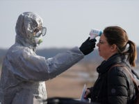SLUBICE, POLAND - MARCH 17: A Polish border guard dressed in a protective suit, mask and goggles takes the body temperature of a Polish woman seeking to enter Poland as an indication of possible coronavirus infection at the Polish/German border at Slubice/Frankfurt (Oder) on March 17, 2020 at Slubice, Poland. …