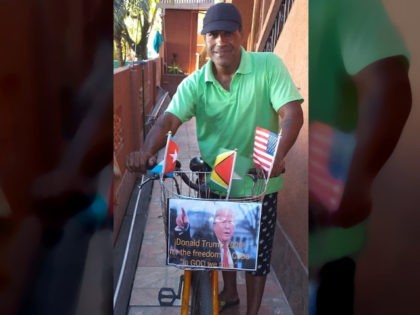 Cuban dissident Daniel Llorente, forced into exile in Guyana, with his bicycle, sporting a photo of Donald Trump and an American flag.