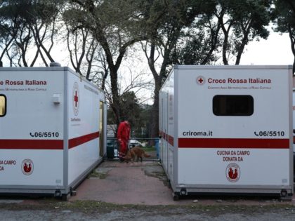 ROME, ITALY - MARCH 17: A member of the Italian Red Cross plays with a dog between two fie