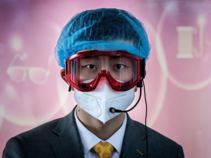 A worker at an information desk wearing protective gear as a preventive measure against the COVID-19 coronavirus looks on at a nearly empty arrivals area at Beijing Capital Airport in Beijing on March 16, 2020. - China tightened quarantine measures for international arrivals as the country worries about a rise …