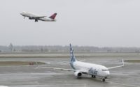 In this April 13, 2018 file photo, a Delta Air Lines plane takes off above a taxiing Alaska Airlines airplane at the Seattle-Tacoma International Airport in Seattle. U.S. airlines are asking the federal government for grants, loans and tax relief that could easily top $50 billion to help them recover …