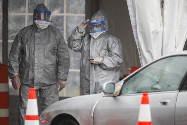 Medical personnel wait for motorists to pull up for COVID-19 coronavirus testing facility at Glen Island Park, Friday, March 13, 2020, in New Rochelle, N.Y. State officials have set up a “containment area” in the New York City suburb, where schools and houses of worship are closed within a 1-mile …