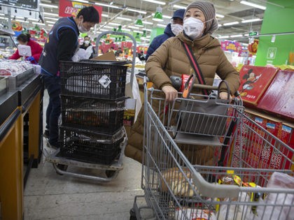 People wear face masks as they shop for groceries at a supermarket in Beijing, Tuesday, Ja