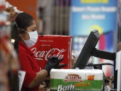 Amid social distancing during the Covid-19 outbreak, a cashier wears a mask while working behind a clear barrier between her and a customer at El Rancho grocery store in Dallas, Thursday, March 26, 2020. For most people, the new coronavirus causes mild or moderate symptoms, such as fever and cough …