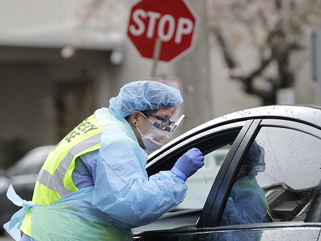 A nurse holds a swab at a drive-up coronavirus testing station at Harborview Medical Center, Thursday, April 2, 2020, in Seattle. The facility saw a steady stream of employees and patients with symptoms Thursday as testing, which has been going on for several weeks, continued as part of efforts to …