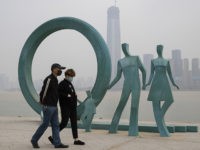 Residents wearing masks against the coronavirus walk past sculpture along the banks of the Yangtze River in Wuhan in central China's Hubei province on Friday, April 3, 2020. (AP Photo/Ng Han Guan)