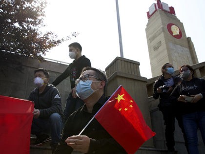 People hold Chinese flags as they gather outside of a park where an official memorial was held for victims of coronavirus in Wuhan in central China's Hubei Province, Saturday, April 4, 2020. With air raid sirens wailing and flags at half-mast, China held a three-minute nationwide moment of reflection to …
