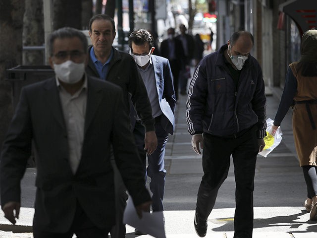 People wearing face masks to protect against the new coronavirus walk on a sidewalk in nor