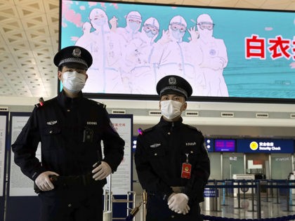 Police officers wearing face masks to protect against the spread of new coronavirus stand